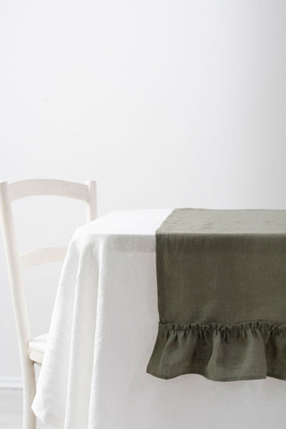 Olīvzaļš lina galda celiņš ar volāniem uz galda