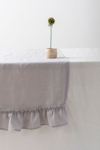 gaiši pelēks lina celiņš ar volānu un vāzi