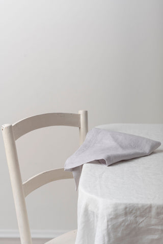 gaiši pelēkas lina salvetes salocīta uz galda