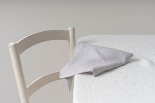 gaiši pelēkas lina salvetes uz balta galdauta