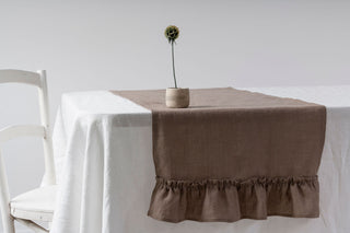 Brūns lina galda celiņš ar volāniem ar baltu galdautu