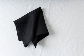 Melna lina salvete uz balta galdauta